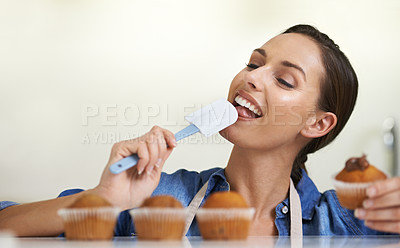Buy stock photo Baking, cupcakes and woman with spatula in kitchen tasting sweet chocolate frosting for dessert. Cooking, eating and young female baker working on muffins and licking tool at home or apartment.