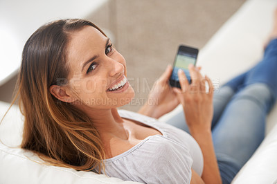 Buy stock photo Shot of a woman looking over her shoulder while using her phone