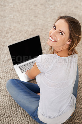 Buy stock photo A young woman sitting on her living room carpet with her laptop