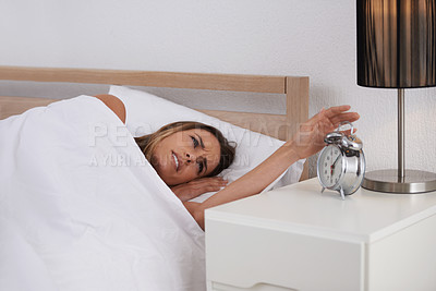 Buy stock photo Woman, bed and alarm in bedroom for upset, tired and sleepy for morning, awake and annoyed at home. Young person and moody with clock on bedside table for time and hour for late with blanket