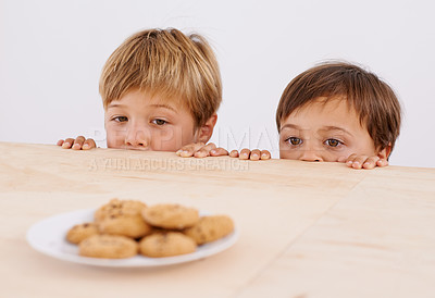 Buy stock photo Children, table and peeking at cookies for curiosity, observation and sneaking with glance. Anticipation, wonder and kids by desk with biscuits for hunger, hiding and playful brothers at home
