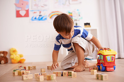Buy stock photo Shot of a little boy playing with his building blocks and toy truck in his room