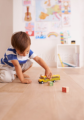 Buy stock photo Shot of a cute little boy playing with his toys in his room