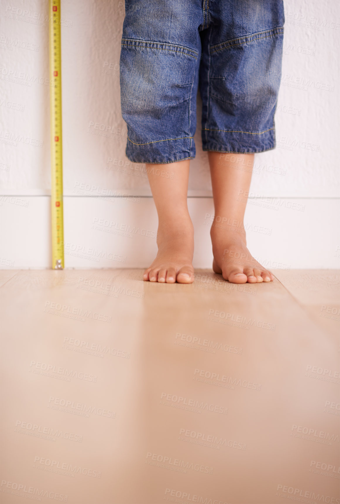 Buy stock photo Child, wall and kid with tape measure for height, tracking growth or progress with feet in house. Legs, toddler and little person with development for size, length and stand on wooden floor at home