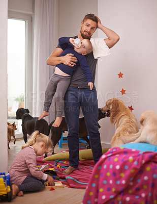 Buy stock photo An overwhelmed dad surrounded by his kids and dogs