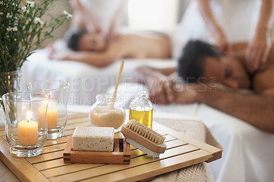 Buy stock photo Candle, brush and couple in spa to relax on bed with luxury pamper treatment tools on table in hotel. Beauty, facial oils or woman with man at resort or salon for natural healing benefits or massage