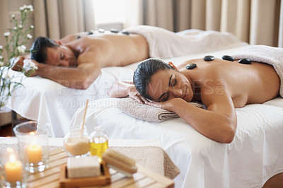 Buy stock photo Spa, wellness and hot stone massage with couple on bed or table for luxury pamper treatment together. Beauty, relax or detox with husband and wife at resort or salon for natural stress relief