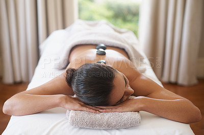 Buy stock photo Relax, rocks and woman at spa for massage, peace and calm for skincare at luxury resort. Beauty, therapy and person at salon with hot stone on back for body treatment, health or rest for wellness
