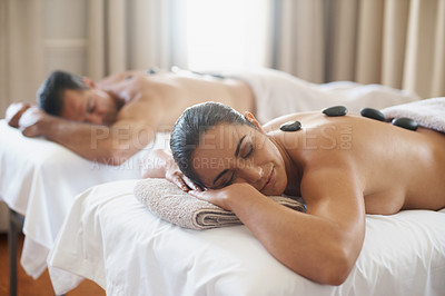 Buy stock photo Spa, love and hot stone massage with couple on bed or table for luxury pamper treatment together. Beauty, wellness or relax with husband and wife at resort or salon for natural stress relief