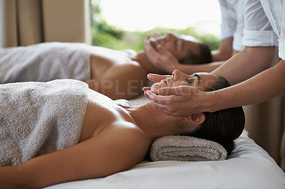 Buy stock photo Hands, face massage and couple in spa to relax on bed for luxury pamper treatment together in hotel. Beauty, facial or zen woman with man at resort or salon for natural healing benefits or skincare