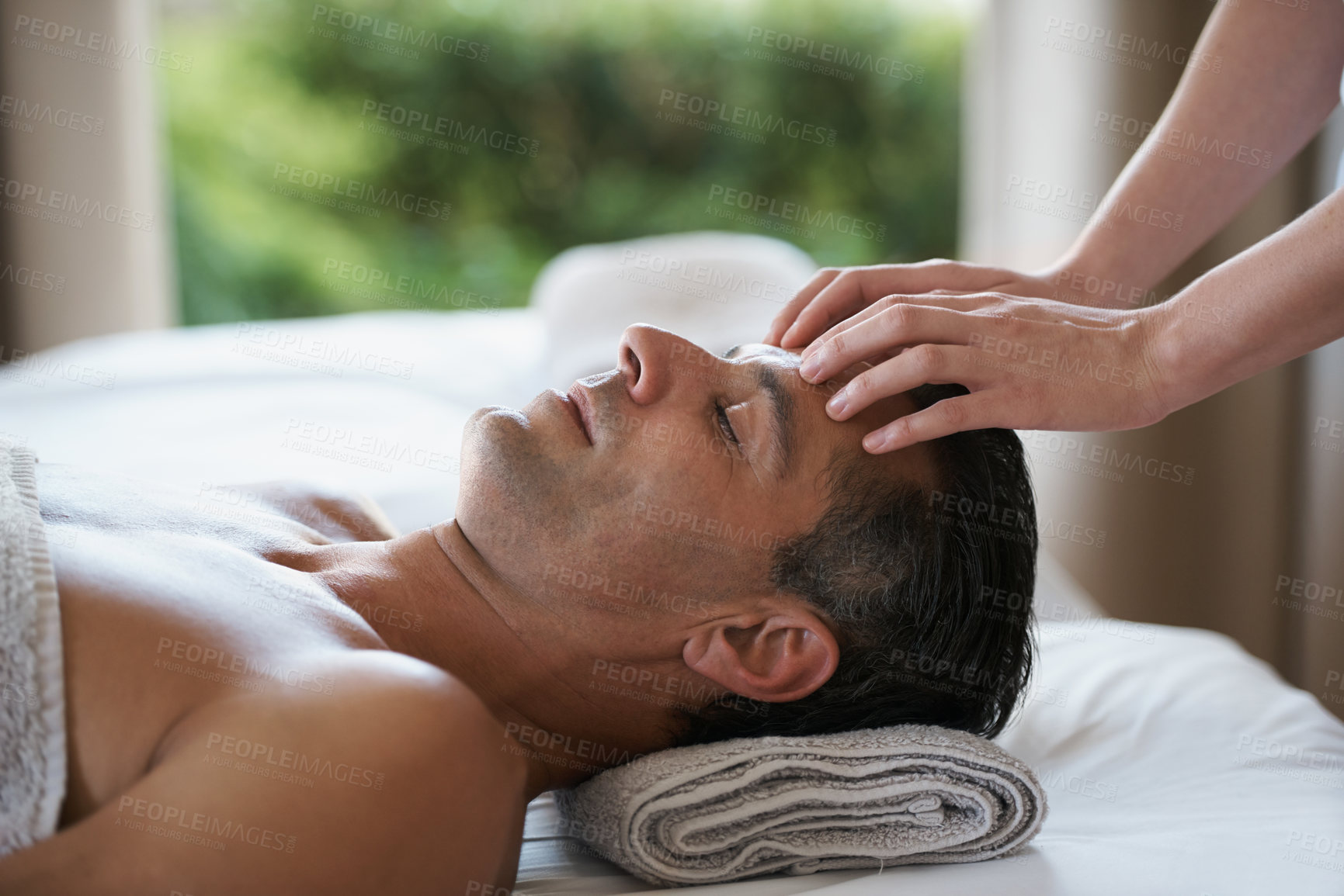 Buy stock photo Relax, head massage and man at salon for skincare, peace and calm at luxury resort at table for wellness. Beauty, therapy and masseuse at spa for face treatment, health and hands of person pampering