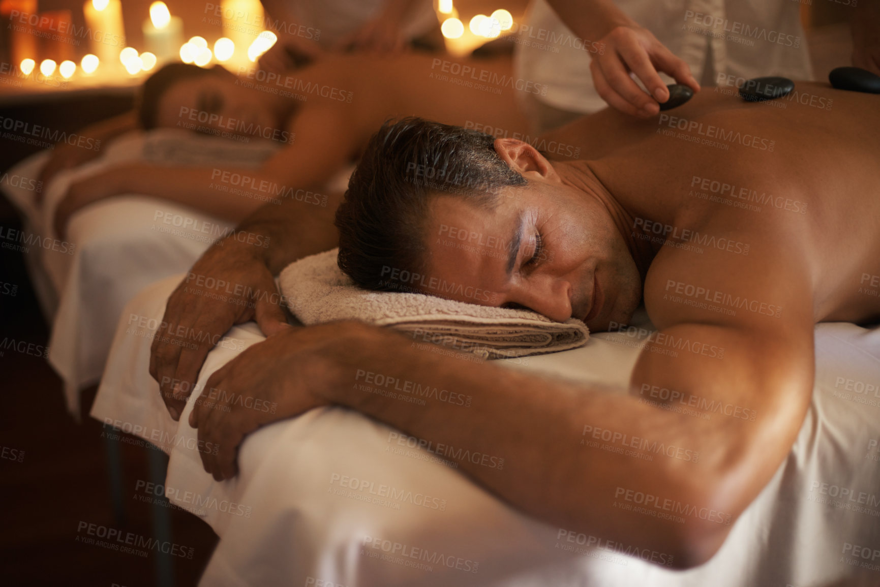 Buy stock photo Couple, hot stone massage and treatment spa with masseuse, wellness and zen for body care at luxury resort. Physical therapy, detox and warm rocks for holistic healing with people for stress relief