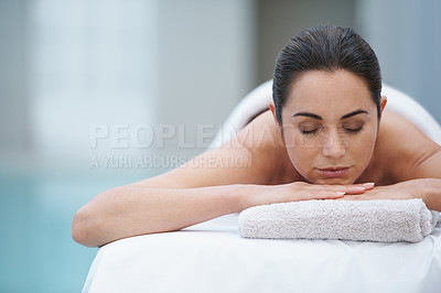 Buy stock photo Shot of a beautiful woman lying on a poolside massage table