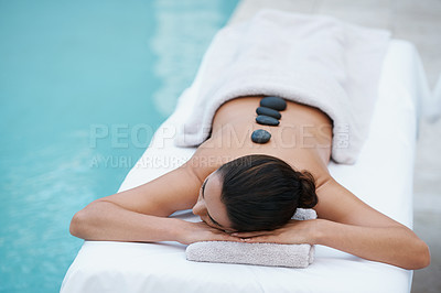 Buy stock photo Relax, hot stone massage and woman at pool at spa for health, zen wellness and luxury holistic treatment. Self care, peace and girl on table for body therapy, comfort and calm pamper service at hotel