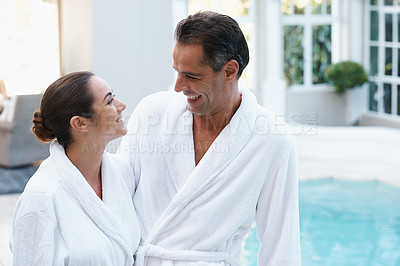 Buy stock photo Smile, robe and couple at hotel pool with embrace, smile or relax together at wellness spa holiday. Hospitality, happy woman and man hug at luxury villa for travel, vacation and love on romantic date