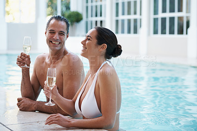 Buy stock photo Couple, pool and drinking alcohol on vacation together, romance and champagne for conversation at hotel. Happy people, summer holiday and love or bonding in water, outdoor date and laugh on honeymoon