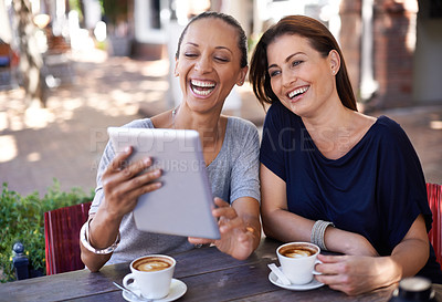 Buy stock photo Two young women looking at a tablet in a coffee shop