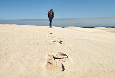 Buy stock photo Person, hiking and walking on sand dunes for fitness adventure in desert and extreme sport in arid climate. Athlete, back or survival gear for nature exploration, footprints or wanderlust vacation