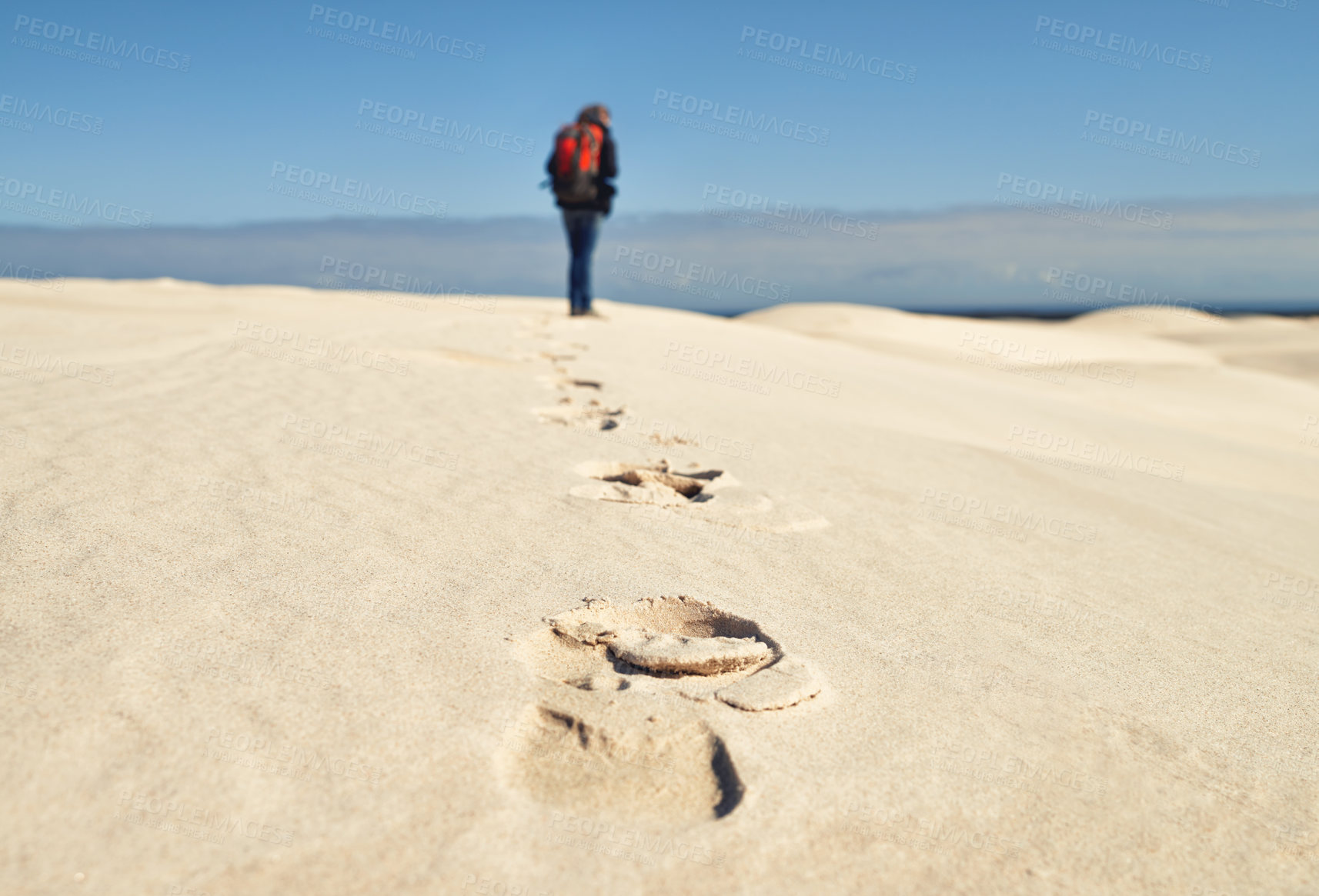 Buy stock photo Person, hiking and walking on sand dunes for fitness adventure in desert and extreme sport in arid climate. Athlete, back or survival gear for nature exploration, footprints or wanderlust vacation