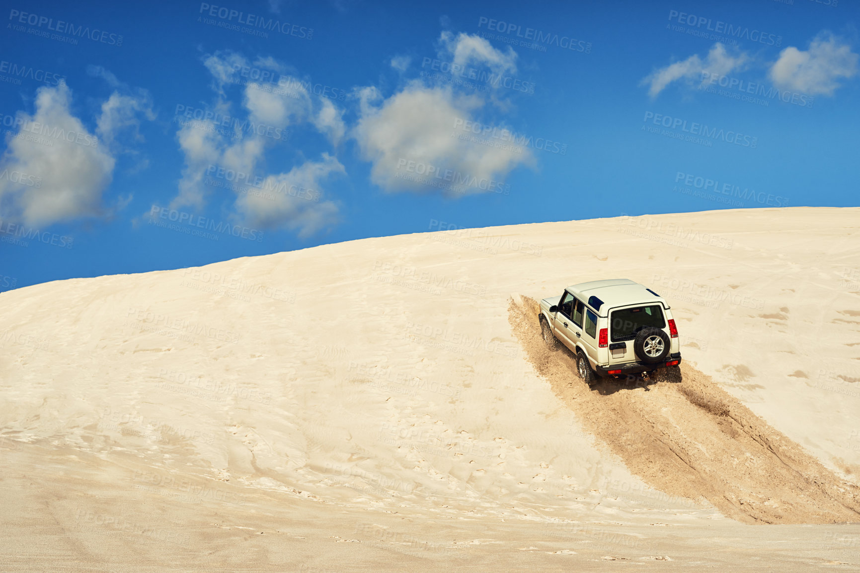 Buy stock photo Shot of a heavy duty 4x4 driving along some sand dunes