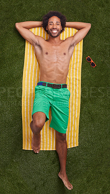 Buy stock photo Happy man, portrait and lying with towel on green grass above for relaxation or outdoor summer holiday. Top view of young male person with smile in relax for swimwear or fashion on field in nature