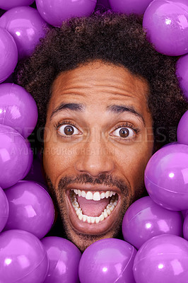 Buy stock photo Ball pit, excited and portrait of black man with plastic toys for fun, playful and happy on background. Surprise, facial expression and face of person with purple balls, decoration and objects
