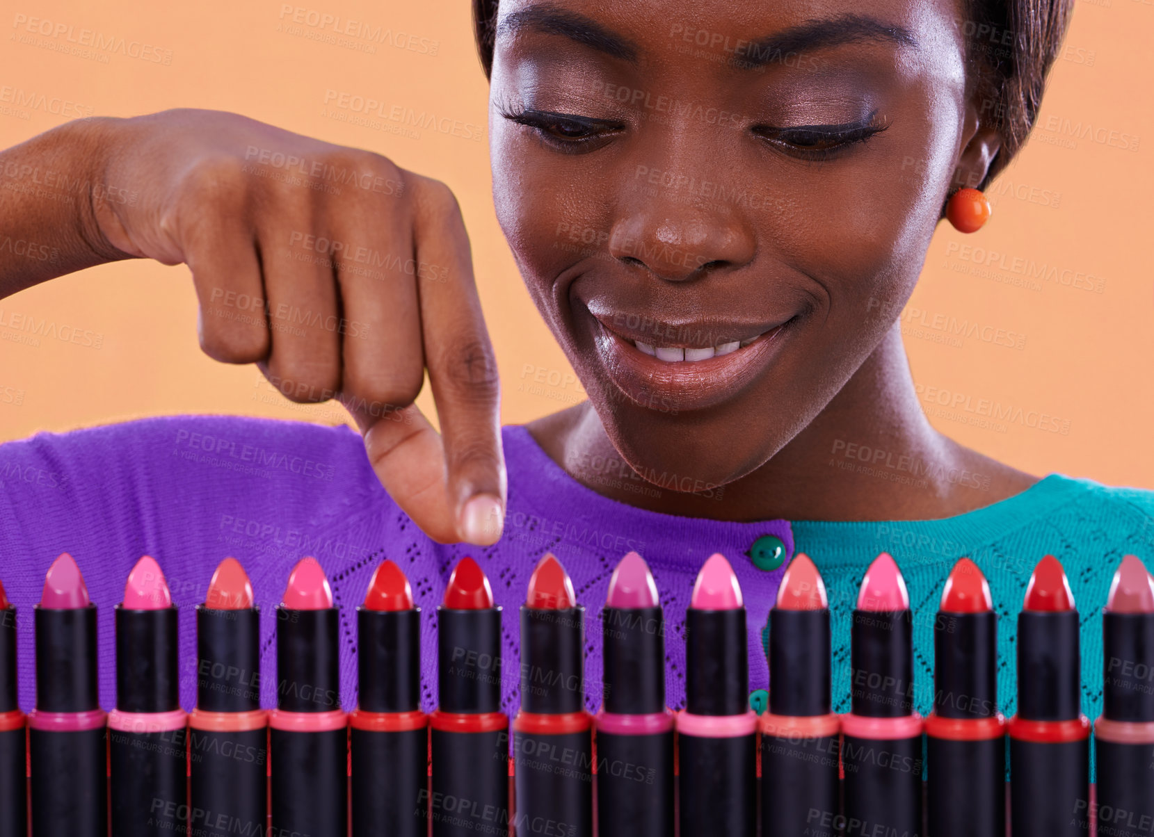 Buy stock photo A young african woman looking over a row of colorful lipsticks