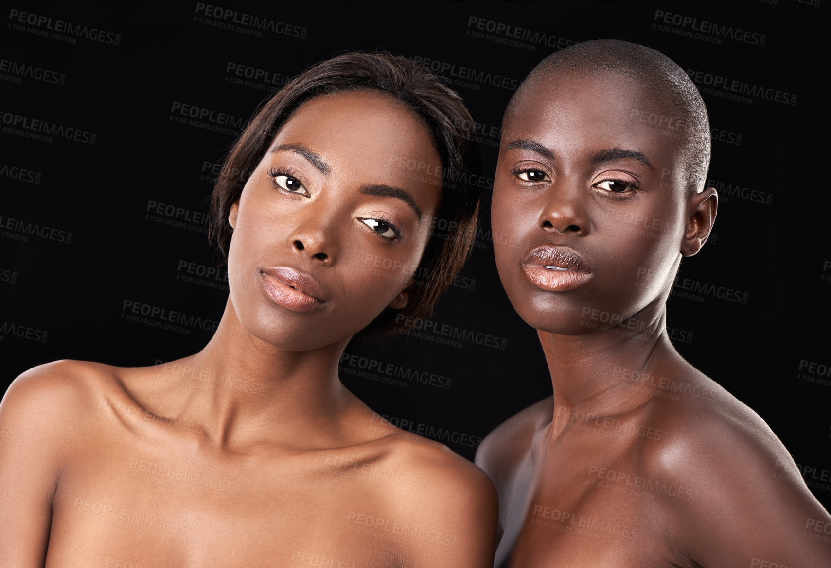 Buy stock photo Two beautiful african women posing in front of a black background with bare shoulders