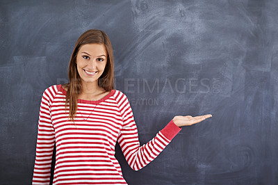 Buy stock photo Portrait of a gorgeous young woman standing in front of a blackboard