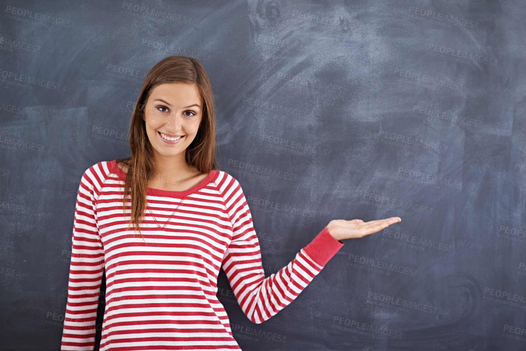 Buy stock photo Portrait of a gorgeous young woman standing in front of a blackboard