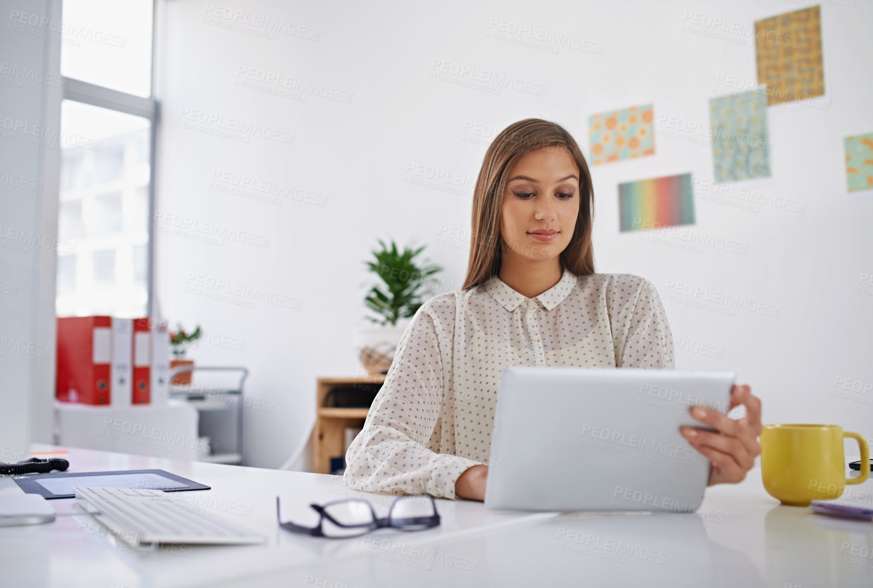 Buy stock photo Shot of a young woman using her digital tablet in the office