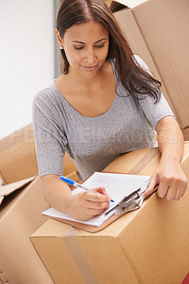 Buy stock photo A beautiful young woman signing a delivery sheet in her new home