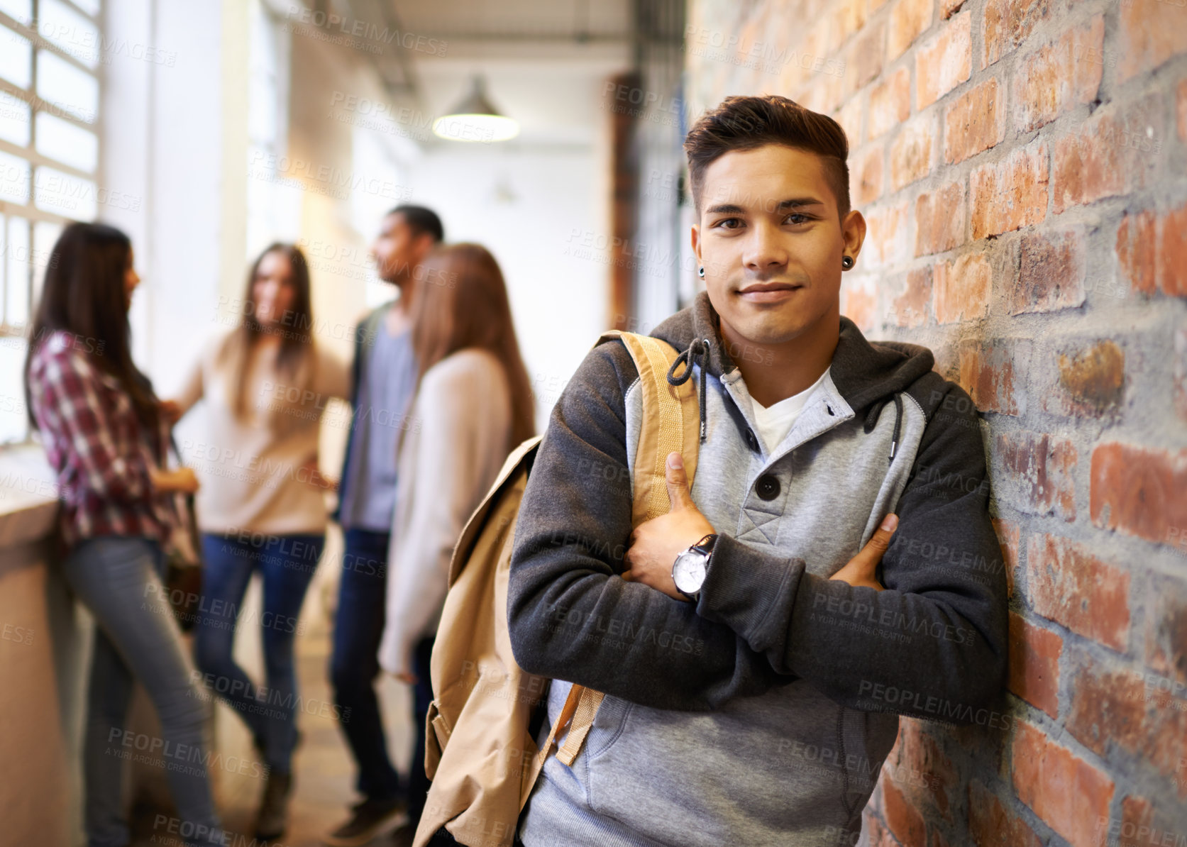 Buy stock photo Portrait of a handsome young male student leaning against a wall with his friends in the background