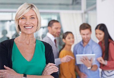 Buy stock photo A portrait of a happy businesswoman standing in an office with her coworkers in the background