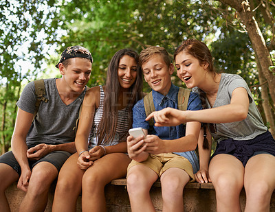 Buy stock photo Friends, smile and phone for browsing social media, together and support outdoors. People, nature and group of teens on jetty for bonding, internet and app or website for funny meme or conversation