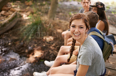 Buy stock photo Nature, smile and portrait of girl with friends sitting in woods for camping trip on vacation. Happy, adventure and face of teenager with group of young people in outdoor forest for holiday together.