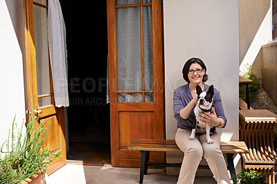 Buy stock photo Shot of a woman sitting on a bench outside her house with her dog