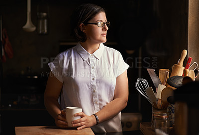 Buy stock photo Shot of an attractive young woman drinking tea in her kitchen