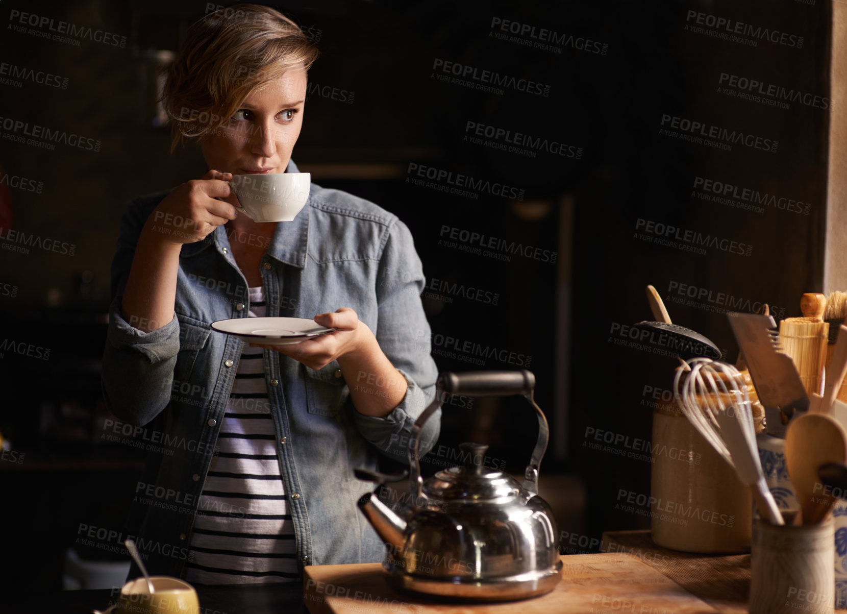 Buy stock photo Shot of an attractive young woman drinking tea in her kitchen