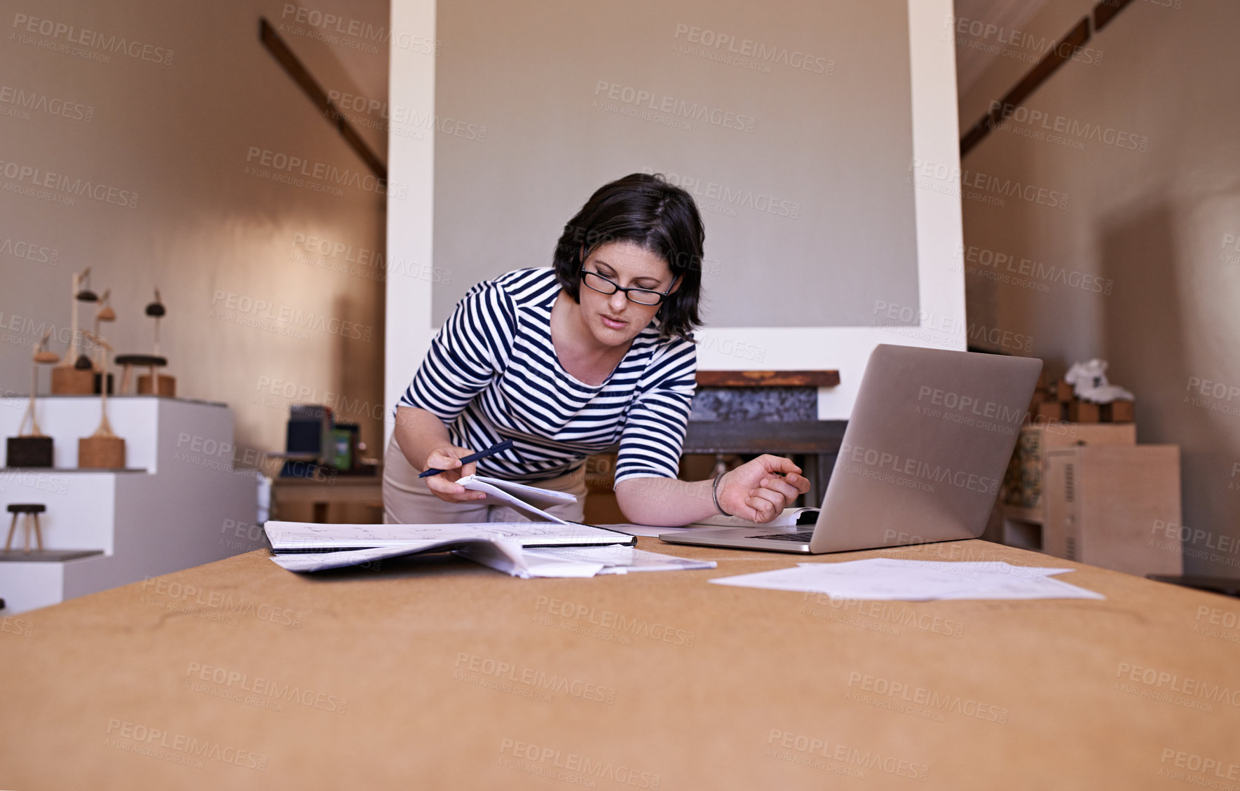 Buy stock photo A cropped shot of a woman standing at her desk and working on her laptop