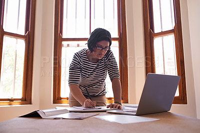 Buy stock photo A cropped shot of a woman standing at her desk and working on her laptop