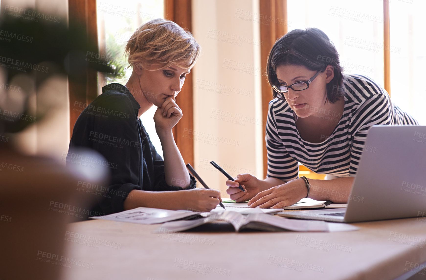 Buy stock photo A cropped shot of two focused women working together in a home office