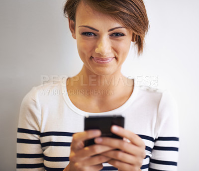 Buy stock photo A cropped portrait of a beautiful young woman using a smartphone