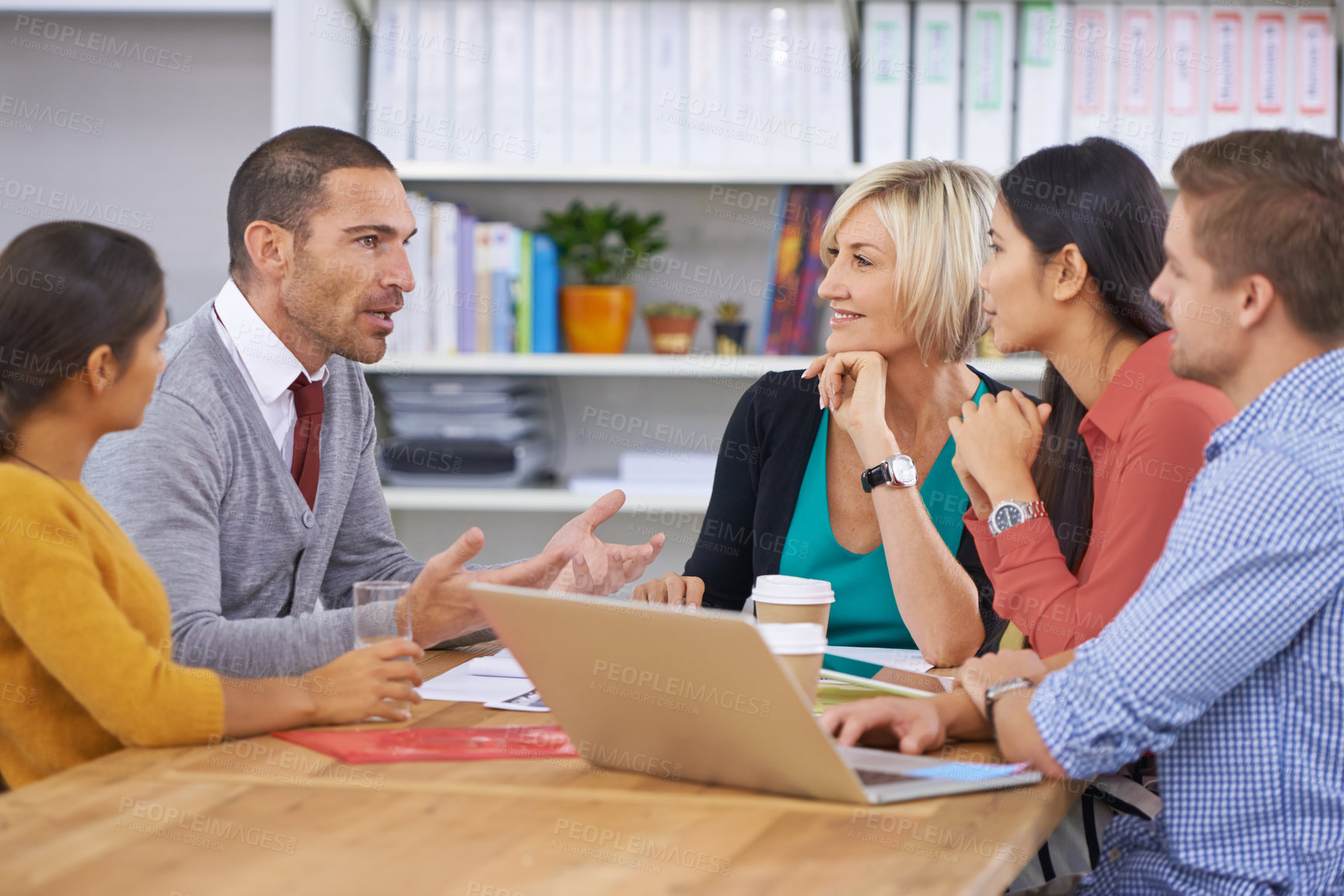 Buy stock photo A group of coworkers talking while sitting around a table
