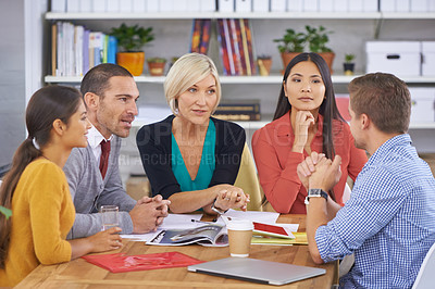Buy stock photo A group of businesspeople talking while sitting around a table