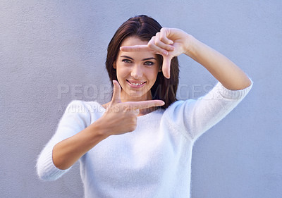 Buy stock photo Portrait, wall and woman with finger frame, smile and focus for creative fashion photography. Perspective, hand gesture and girl showing happy face, casual style and view finder on blue background.