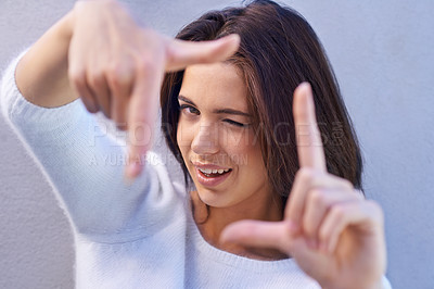 Buy stock photo Happy woman, portrait and framing face with hands for photography, selfie or capture on a gray studio background. Young female person or model with smile or frame for picture moment, memory or photo