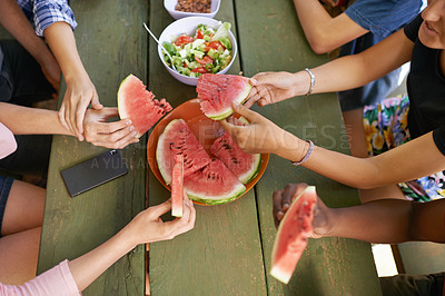 Buy stock photo High angle shot of a group of teenage friends having watermelon while on a picnic