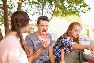 Buy stock photo Picnic, portrait and teenager eating watermelon with friends as group in morning for breakfast. Spring, outdoor and male person in park with classmates to relax, together and fruit as healthy food