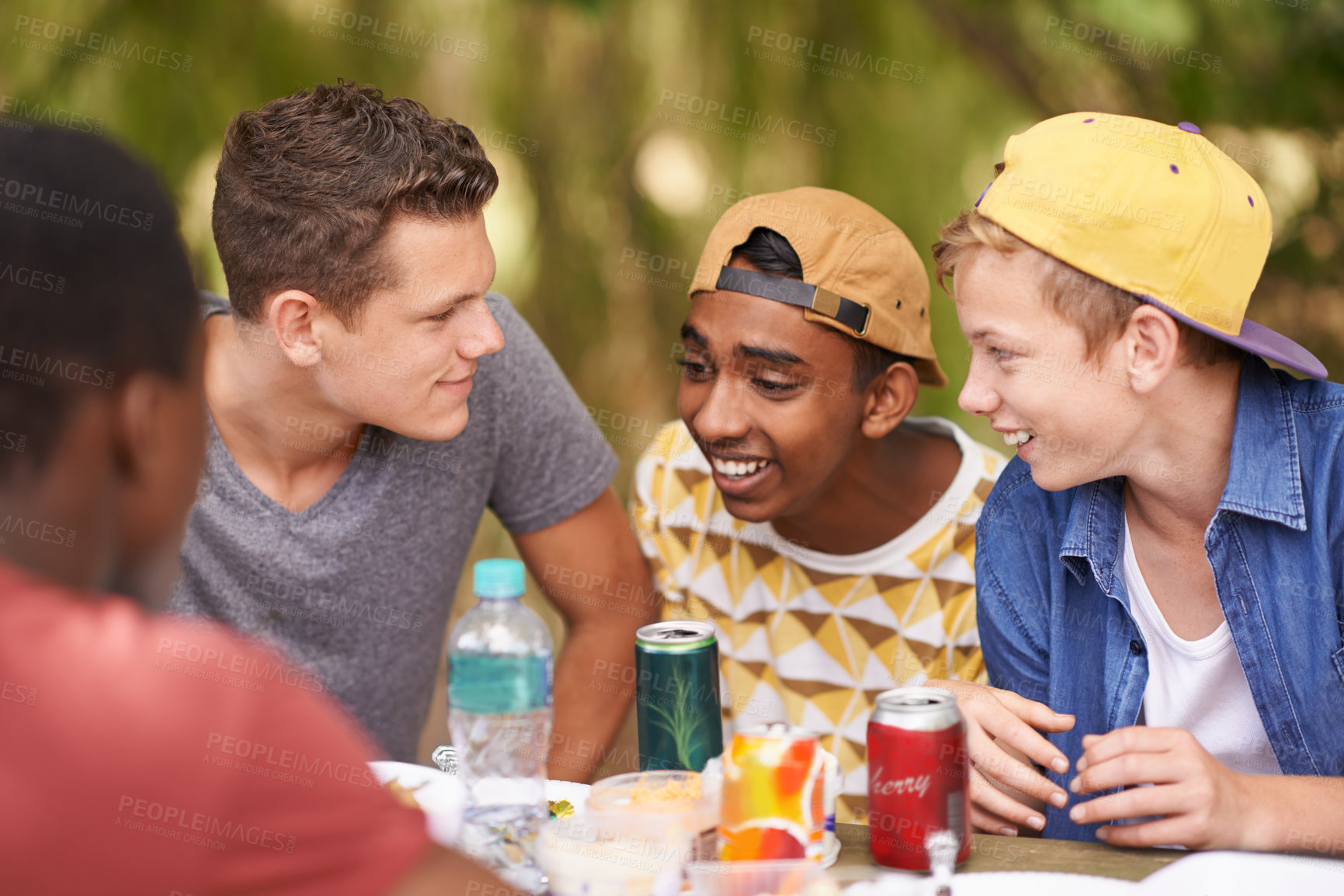 Buy stock photo Shot of a group of teenage boys having a picnic at a table in the park